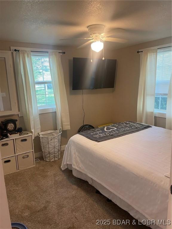 bedroom featuring baseboards, carpet flooring, ceiling fan, and a textured ceiling