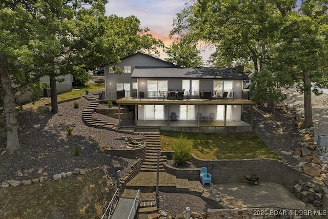 back of house at dusk featuring a patio area, stairway, and a wooden deck
