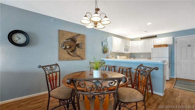 dining space with baseboards, light wood-style floors, and an inviting chandelier