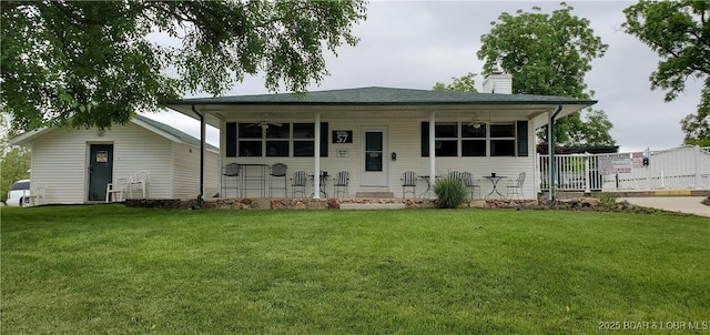 view of front of property with covered porch, a front lawn, and a chimney