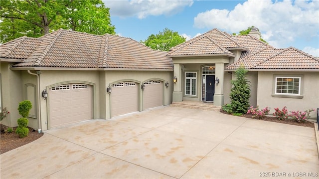 207 Buck Deer Ln, Camdenton, MO 65020 - mediterranean / spanish home featuring concrete driveway, stucco siding, a tiled roof, and a garage