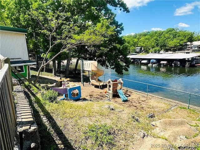 exterior space featuring a playground, fence, and a water view