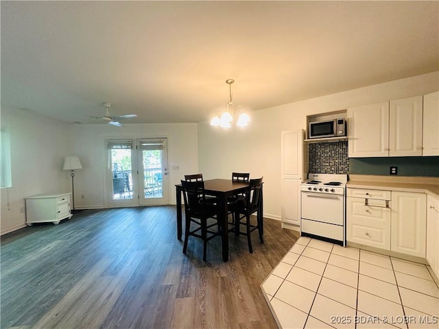 dining room with ceiling fan with notable chandelier, baseboards, and light wood-style floors