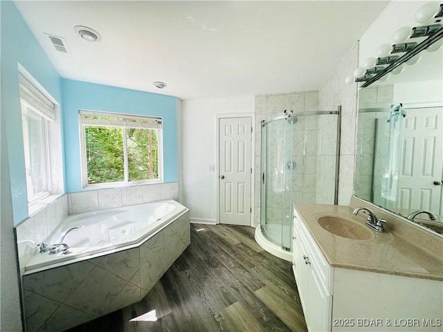 bathroom featuring wood finished floors, vanity, a stall shower, baseboards, and a bath