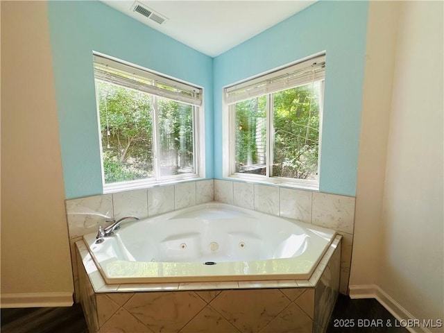 full bathroom featuring baseboards, a tub with jets, and visible vents