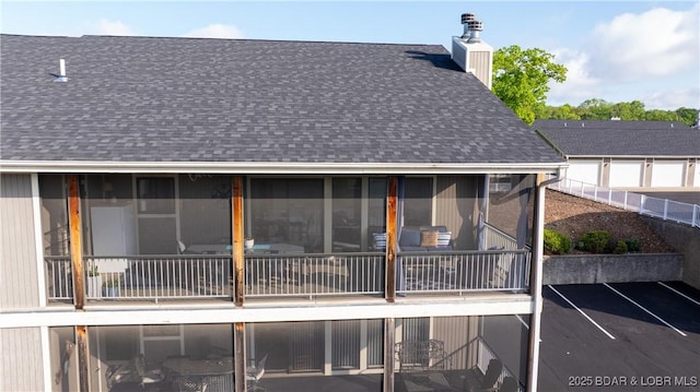 611 Lazy Days Rd Unit L5, Osage Beach, MO 65065 - back of property featuring a sunroom, roof with shingles, and a chimney