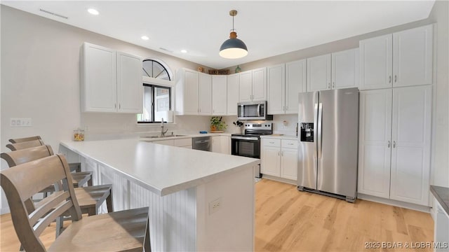 611 Lazy Days Rd Unit L5, Osage Beach, MO 65065 - kitchen featuring light wood finished floors, a sink, a kitchen breakfast bar, a peninsula, and stainless steel appliances