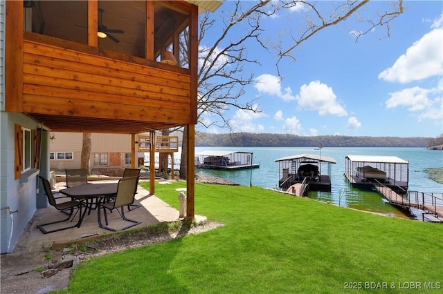 view of green lawn featuring a boat dock, a patio, a water view, and a sunroom