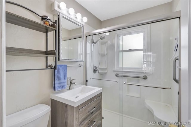 bathroom with toilet, a stall shower, and vanity