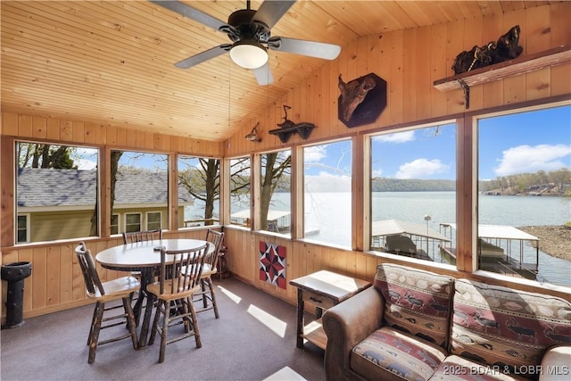sunroom with lofted ceiling, wooden ceiling, wooden walls, a water view, and carpet flooring