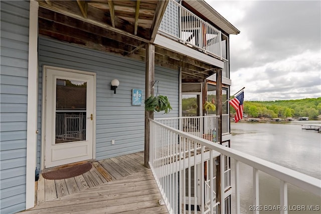 view of exterior entry with a water view and a balcony