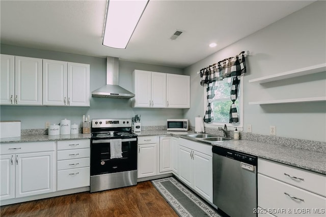 kitchen with white cabinets, wall chimney range hood, appliances with stainless steel finishes, and a sink