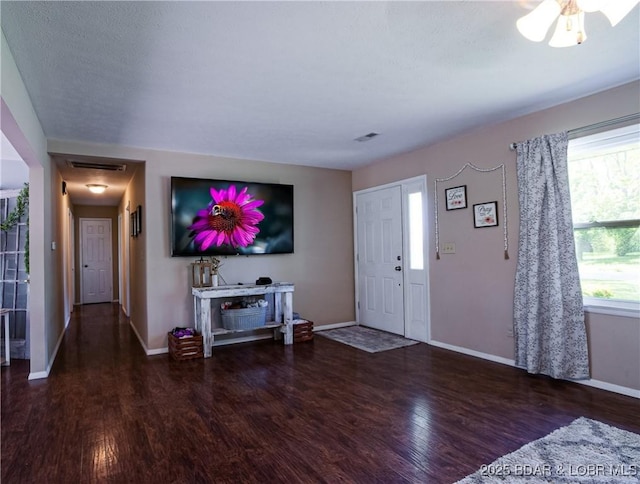 living room with plenty of natural light, visible vents, wood finished floors, and baseboards