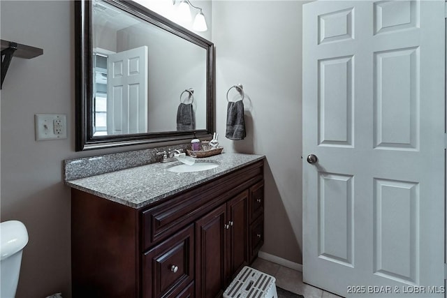 half bathroom with toilet, tile patterned flooring, vanity, and baseboards