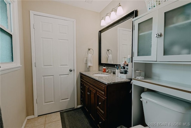 half bath with toilet, baseboards, tile patterned floors, and vanity