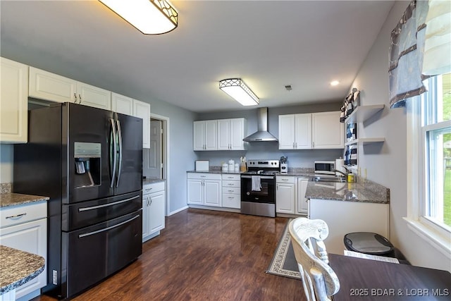 kitchen with stone countertops, wall chimney range hood, white cabinets, appliances with stainless steel finishes, and dark wood-style floors