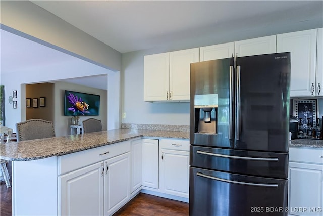 kitchen with fridge with ice dispenser, a peninsula, and white cabinetry