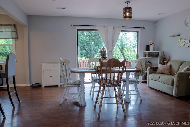 dining room featuring a healthy amount of sunlight, baseboards, dark wood-type flooring, and visible vents