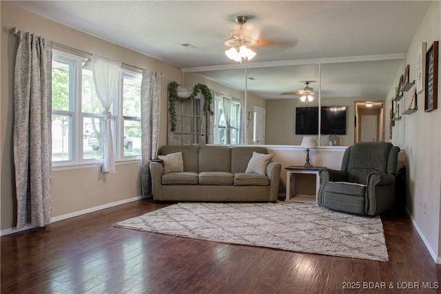 living area with baseboards, a healthy amount of sunlight, and dark wood-type flooring