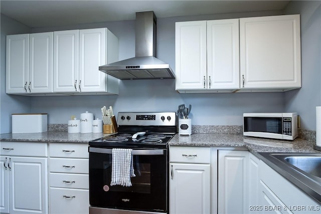 kitchen with white microwave, wall chimney range hood, white cabinetry, and electric range