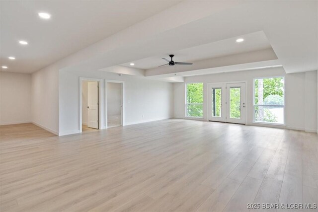 unfurnished living room featuring a ceiling fan, a raised ceiling, baseboards, and recessed lighting