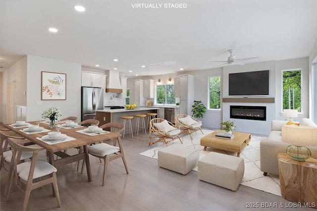 living room featuring light wood finished floors, recessed lighting, ceiling fan, and a glass covered fireplace