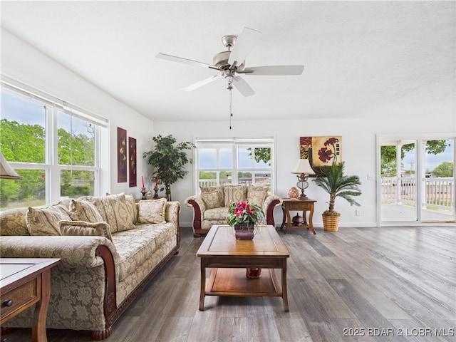 living room featuring baseboards, a ceiling fan, and dark wood-type flooring