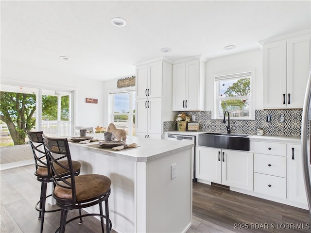 kitchen featuring a breakfast bar, a sink, backsplash, light countertops, and a kitchen island