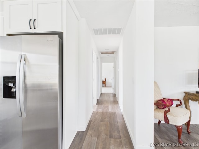 corridor featuring baseboards, visible vents, and wood finished floors