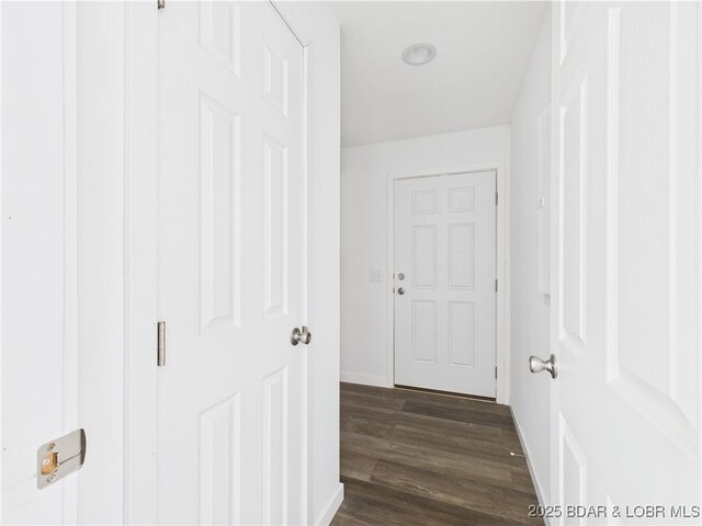 hallway featuring baseboards and dark wood-type flooring