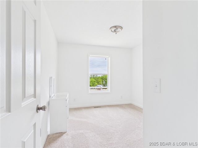carpeted spare room featuring baseboards