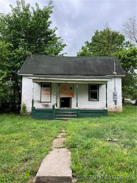 view of front facade featuring a porch, roof with shingles, and stucco siding