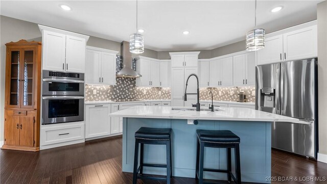 484 Hogan Dr, Lake Ozark, MO 65049 - kitchen featuring appliances with stainless steel finishes, wall chimney exhaust hood, a sink, dark wood-style flooring, and a breakfast bar