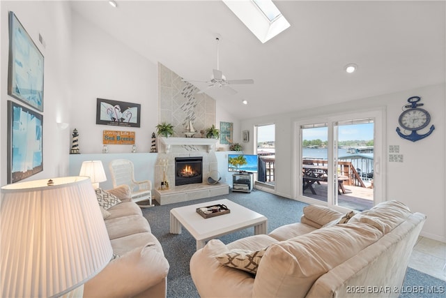 living room featuring high vaulted ceiling, a skylight, a ceiling fan, a fireplace, and recessed lighting