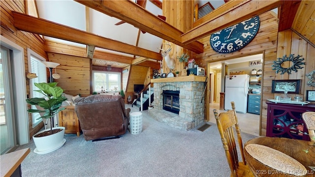 carpeted living room with beam ceiling, high vaulted ceiling, visible vents, a fireplace, and wooden walls