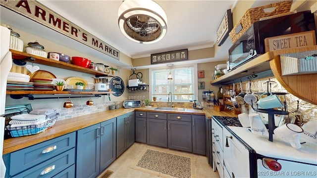 interior space with a sink, open shelves, visible vents, backsplash, and butcher block counters