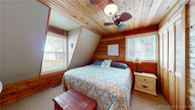 bedroom featuring ceiling fan, visible vents, wood ceiling, wooden walls, and light colored carpet