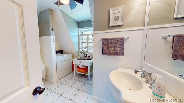 bathroom featuring a ceiling fan, washer / clothes dryer, wainscoting, a sink, and tile patterned floors