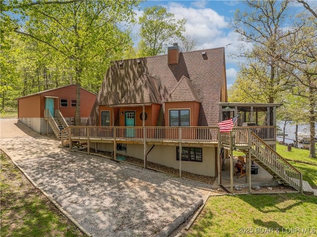 rear view of property with a chimney, a deck, stairway, and a sunroom