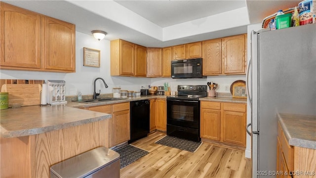 93 Misty Meadows Ln, Camdenton, MO 65020 - kitchen with black appliances, light wood-style floors, a sink, a peninsula, and a raised ceiling