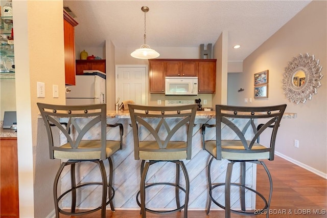 58 Jonathan Dr Unit 4B, Lake Ozark, MO 65049 - kitchen featuring white appliances, dark wood-type flooring, baseboards, hanging light fixtures, and a textured ceiling