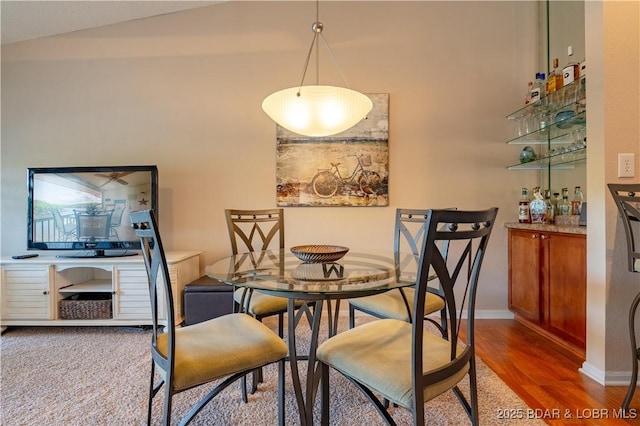 58 Jonathan Dr Unit 4B, Lake Ozark, MO 65049 - dining space featuring wood finished floors, a bar, baseboards, and high vaulted ceiling