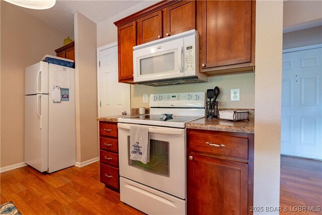 58 Jonathan Dr Unit 4B, Lake Ozark, MO 65049 - kitchen featuring white appliances, wood finished floors, baseboards, a textured ceiling, and brown cabinets