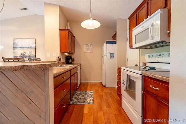 58 Jonathan Dr Unit 4B, Lake Ozark, MO 65049 - kitchen featuring white appliances, a sink, light wood-style flooring, vaulted ceiling, and a peninsula