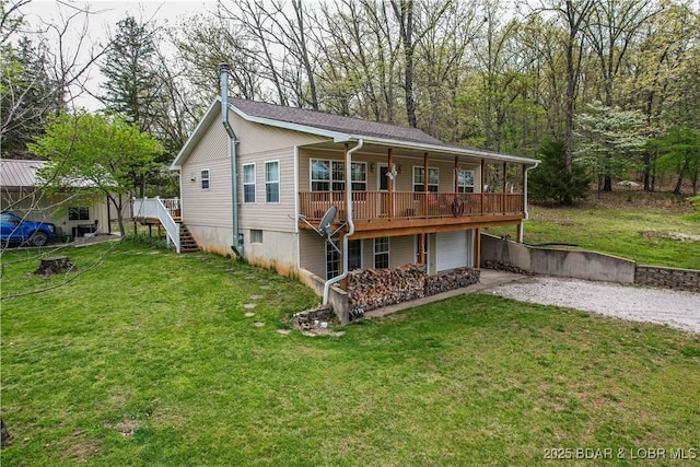 rear view of property featuring gravel driveway, a garage, a lawn, and a deck
