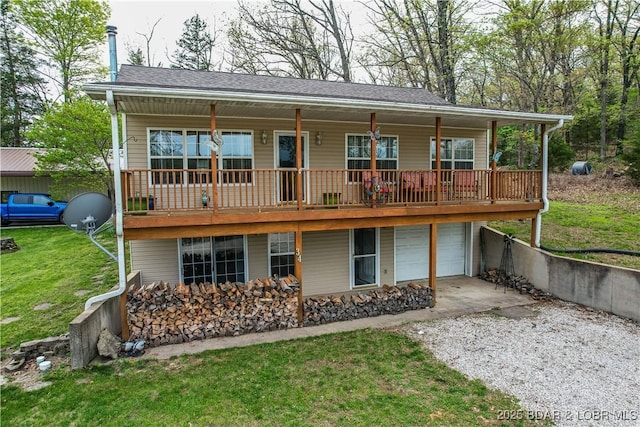 rear view of house with gravel driveway, a yard, and an attached garage