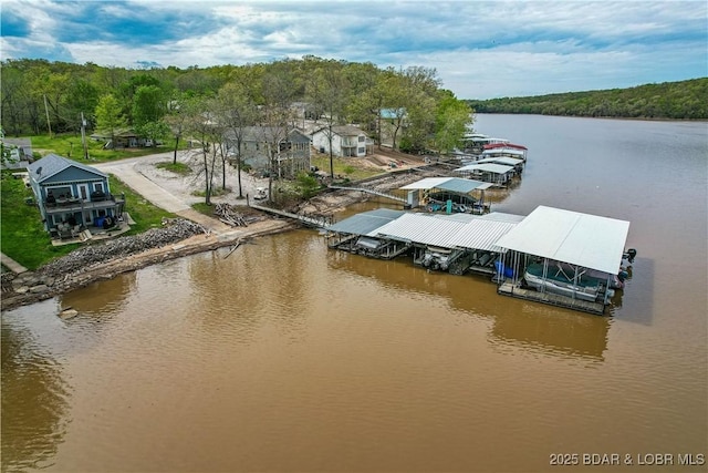dock area with boat lift, a water view, and a wooded view