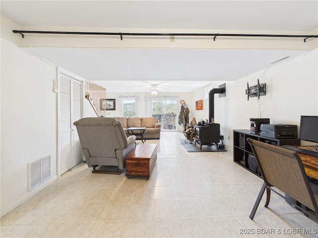 living room with light tile patterned flooring, a wood stove, and ceiling fan