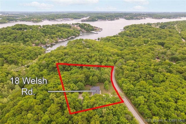 aerial view of property's location featuring a nearby body of water, a heavily wooded area, and property boundaries highlighted