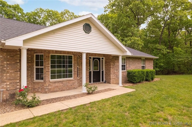single story home featuring a front lawn, brick siding, a porch, and a shingled roof